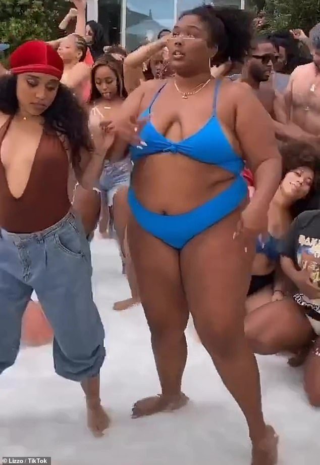 Lizzo shows some skin in a blue bikini while dancing with friends at a pool party