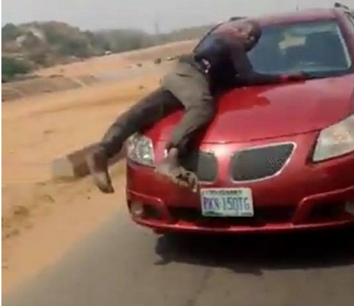 Policeman spotted on bonnet of speeding vehicle of lady who refused to stop for security operatives who were not wearing face masks (video)